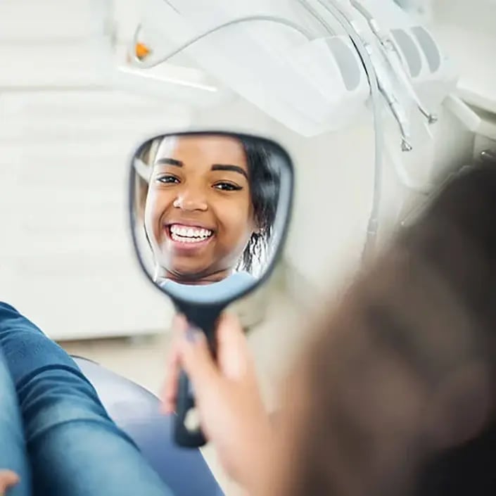 happy-female-patient-looking-in-mirror-705x705